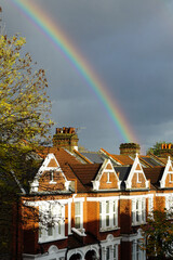 London, England - A double rainbow appearing to end behind a row of typical English terraced houses, against a stormy grey sky.  Image has copy space.