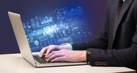 Businessman working on laptop with SOLAR ENERGY inscription, cyber technology concept