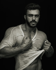 Portrait of handsome male fitness model holding his wet tshirt in sepia tone
