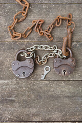 Two old rusty padlock and rusty chain on wooden background . High quality photo
