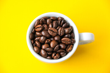 Kaffeetasse mit Bohnen vor gelbem Hintergrund