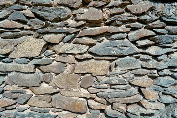 Natural old stone wall texture close-up. Stone wall cladding made of brown and gray natural rocks.