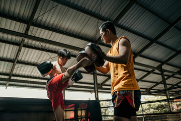 Fototapeta na wymiar kickboxer and coach training together with punching pads at boxing training camp