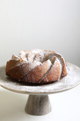 Homemade bundt cake with powder sugar on a white table.