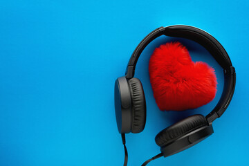 Fototapeta na wymiar Red heart and black headphones on a blue background. Love music lifestyle concept. Valentine's Day