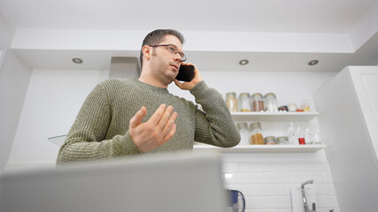 Upset man talking on the mobile phone. Doing business from home.