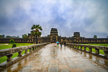 Fototapeta premium Angkor Wat-largest temple in the world. It is raining. Tourists walk around the temple