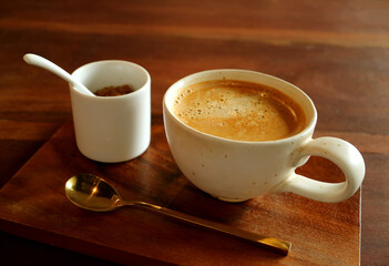 Hot coffee with brown sugar pot and brass teaspoon on wooden table