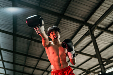 Young man looking aggressive with boxing gloves make a punch motion on boxing ring background