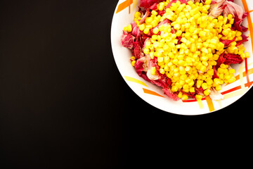 Salad with corn on black table, top view