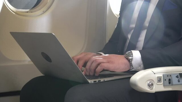 businessman working on laptop computer sitting inside an airplane with sun light