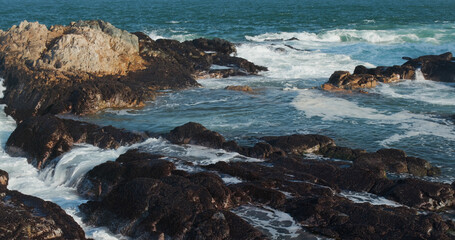 Sea waves splash against rock on island