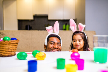 happy mixed race family celebrating Easter, painting eggs with brush smiling and laughing