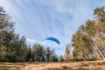 Startender Hobby Gleitschirm Flieger an einem Berghang mit professioneller Ausrüstung im Herbst,...