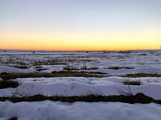 Snow covered cultivation fields at sunset 