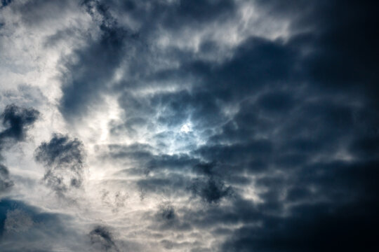 Evening sky with dramatic clouds illuminated by the full moon at the blue hour. 