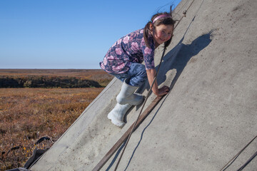 The extreme north, Yamal, the past of Nenets people, the dwelling of the peoples of the north, a girl playing near the yurts in the tundra