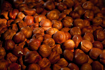 Peeled hazelnuts close up. Texture of nuts. Lots of nuts in a pile. Contrasting dramatic light as an artistic effect.