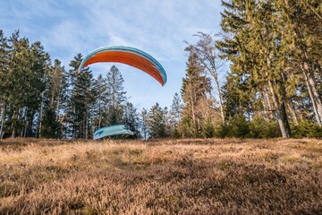 Startender Hobby Gleitschirm Flieger an einem Berghang mit professioneller Ausrüstung im Herbst,...