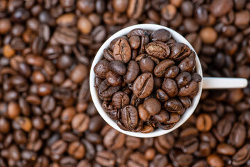 Fototapeta premium coffee beans close up and a cup full of coffee beans, top view
