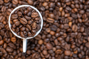 coffee beans close up and a cup full of coffee beans, top view