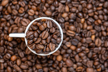 coffee beans close up and a cup full of coffee beans, top view