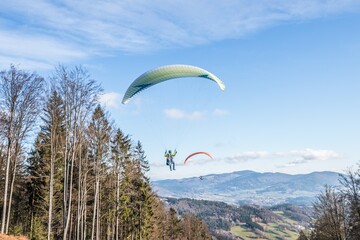 Fliegender Hobby Gleitschirm Flieger an einem Berghang mit professioneller Ausrüstung im Herbst mit Aussicht auf Berge und Alpen im Hintergrund, Deutschland