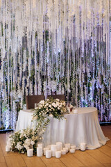 The presidium of the newlyweds in the banquet hall of the restaurant is decorated with candles and green plants