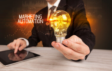 Businessman holding lightbulb with MARKETING AUTOMATION inscription, Business technology concept