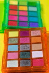 A palette of bright cosmetics. Cosmetics on a yellow background. Bright eye shadow.