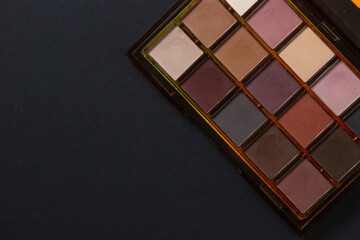 A palette of cosmetics. Cosmetics on a black background. Warm eye shadow.