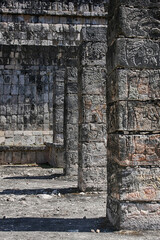 Obraz premium Chichen Itza - stone columns adorned with Mayan civilization creating a corridor and illuminated by the sun's rays.