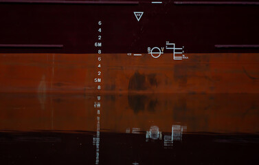Plimsol line and draught lines on the steel hull of a large cargo ship.