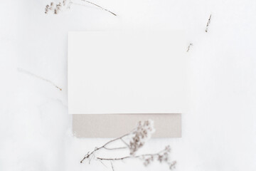 White sheet on gray cardboard mock up. Blank sheet of paper lying in the snow, top view. Empty space for text, branding, message.