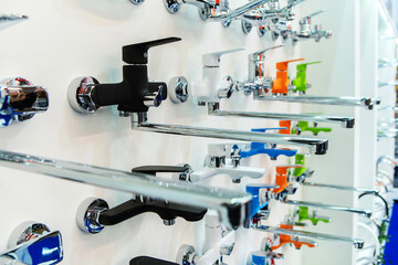 Assortment of bathroom taps in a plumbing store. Large selection of multi-colored faucets in the wholesale and retail network