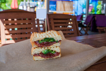 a sandwich on a wooden table in a summer cafe. fresh vegetables, sun-dried tomatoes, bread, cheese, salami. Isolated on a wooden background