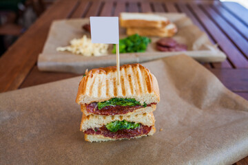 a sandwich on a wooden table in a summer cafe. fresh vegetables, sun-dried tomatoes, bread, cheese, salami. Isolated on a wooden background