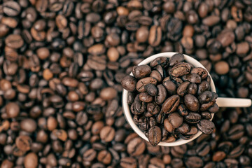 coffee beans close up and a cup full of coffee beans, top view