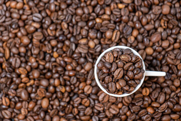 coffee beans close up and a cup full of coffee beans, top view