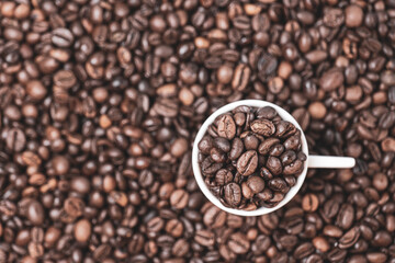 coffee beans close up and a cup full of coffee beans, top view