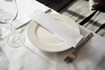 serving the table. white empty plate with napkin, knife and fork. festive banquet. service in a restaurant or cafe.