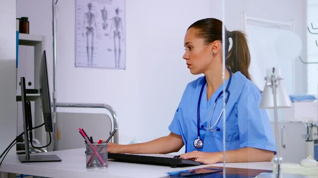 Medical woman nurse typing on computer patient health report, sitting in hospital office. Healthcare physician in medicine uniform writing treatments making appointments checking registration.