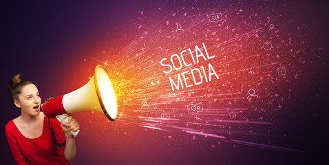 Young woman yelling to loudspeaker with SOCIAL MEDIA inscription, social networking concept