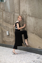 Blond european young woman standing near wall