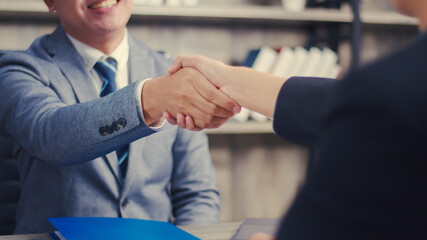 Asian businessman shaking hands partnership deal business while standing indoors in the office, Happy confident accept handshaking employer getting hired at a new job. © Lifehdfilm