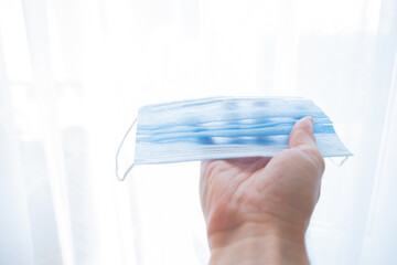 
hand holds a medical face mask against viruses and bacteria on a white background. Pandemic Covid-19. medicine and quarantine concept
