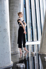 Young white model girl standing on the floor among concrete columns