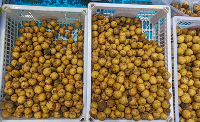 langsat, lansium, or duku pile in a white basket sale in market. Top view of duku.display for selling grocery store . longkong fruits. Thailand fruits