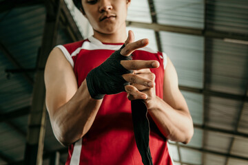 portrait of boxer fighter applying bondage tape on hands over fighting place background