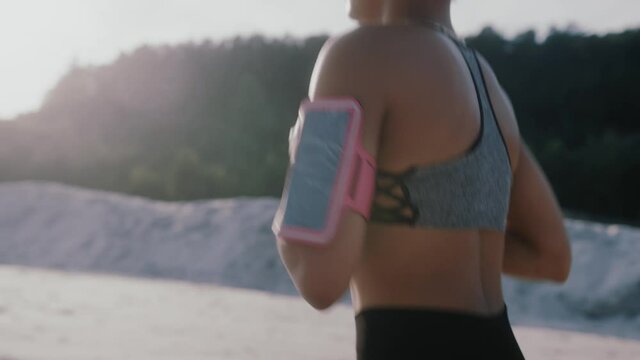 Slow motion young african american fitness woman listening music on headphones trail runner running on sand desert dunes. Countryside jogger exercise nature sport athlete.